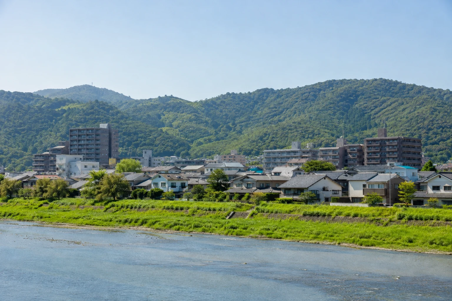 Wohnhäuser und Apartmentgebäude in Minami-ku am Katsura-Fluss vor bewaldeten Hügeln